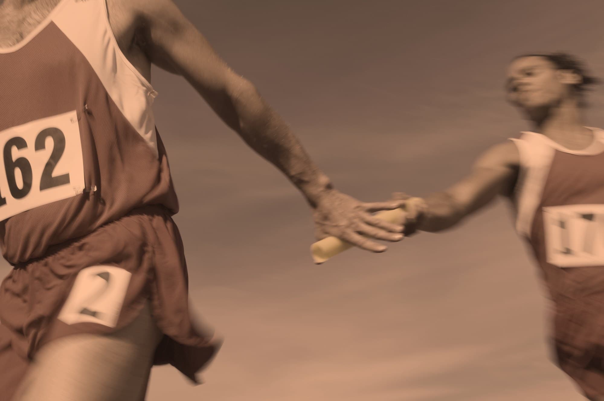 A relay baton passing between two runners